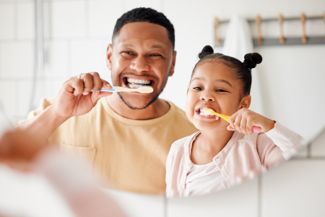 A father brushing his teeth with his daughter